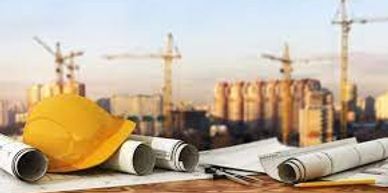 Construction site with blueprints and a hard hat on the table with cranes in the background.