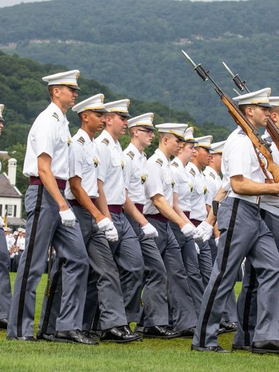 Uniformed cadets march in formation during a ceremonial event.