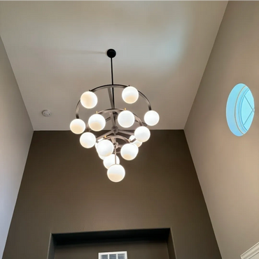 Modern chandelier with spherical lights in a high-ceiling room.