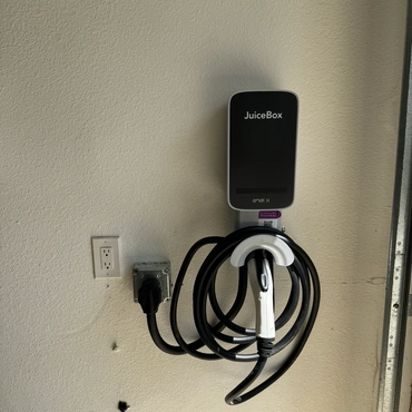 Electric vehicle charging station mounted on a wall with coiled cable.