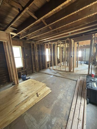 Gut renovation with exposed framing and rafters mid-construction.
