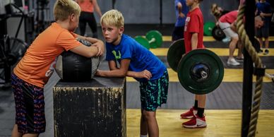 Two boys arm wrestling in a gym.