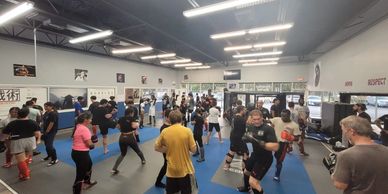 A busy martial arts gym with many people training.