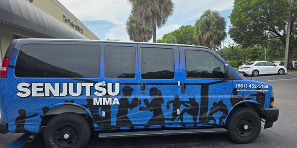 Blue van with Senjutsu MMA advertisement and silhouettes of fighters.