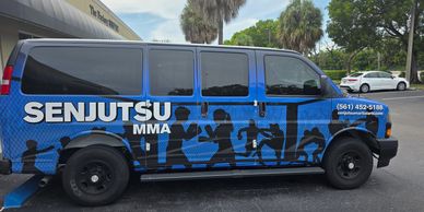Blue van with Senjutsu MMA advertisement and silhouettes of fighters.