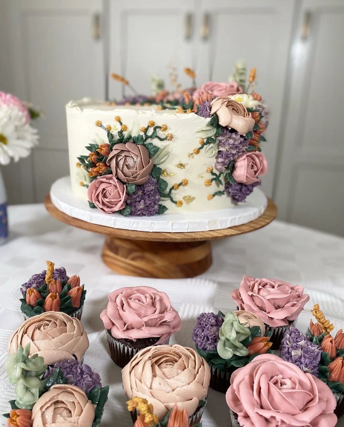 Floral cake and cupcakes with intricate buttercream flowers.