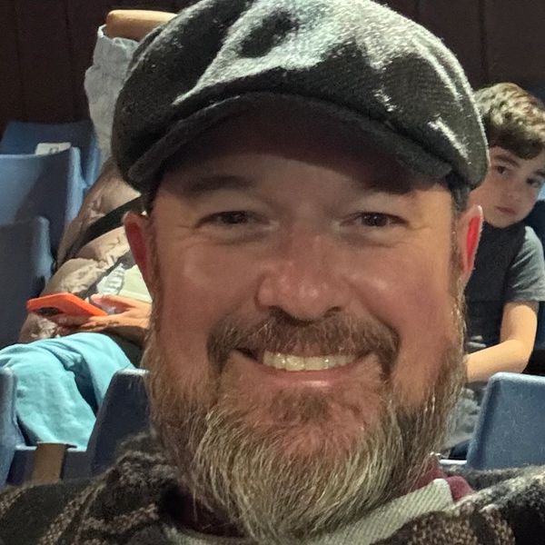Man with a beard and cap smiling.