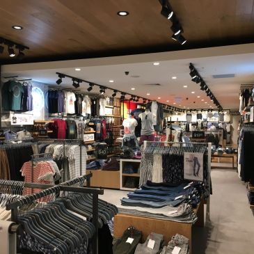 Interior of a modern clothing store with racks and shelves of apparel.