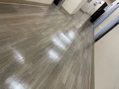 Shiny wooden floor in a clean hallway with doors and light reflections.