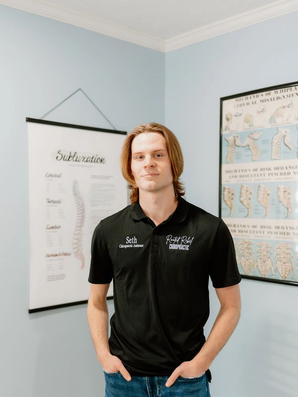 Young man in a chiropractic assistant shirt standing in a clinic.