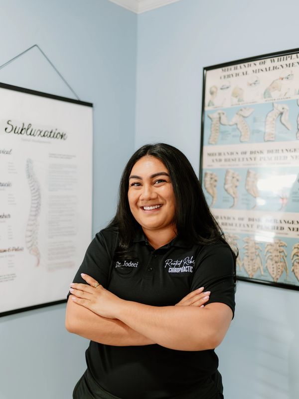 Smiling female chiropractor with arms crossed in a clinic setting.