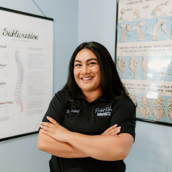 Smiling female chiropractor with arms crossed in a clinic setting.