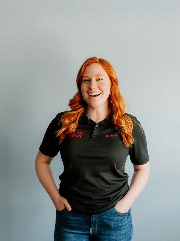 Smiling woman with red hair wearing a black shirt labeled Dr. Joan.