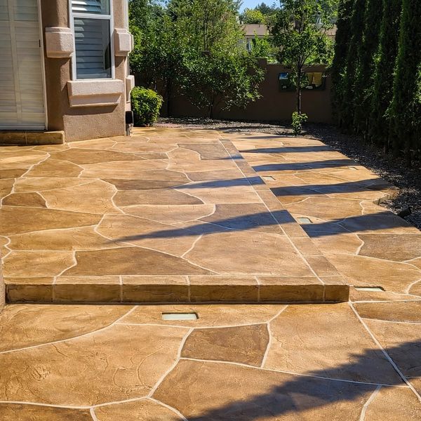 Sunlit stone-paved patio with shadows from nearby trees.