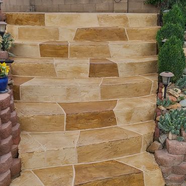 Stone stairs with natural tones leading up to a cinder block wall with blue stripe.