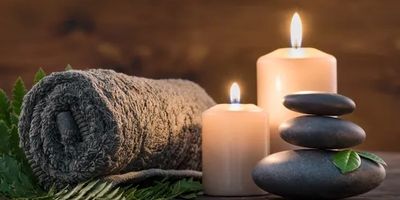 Rolled towel, candles, and stacked stones for relaxation.