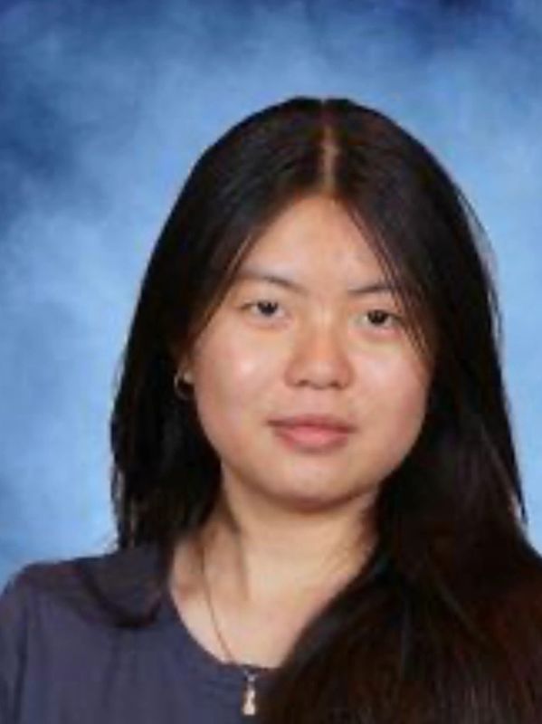 Portrait of a young woman with long dark hair against a blue background.