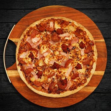 A meat lover's pizza with various toppings on a wooden board.