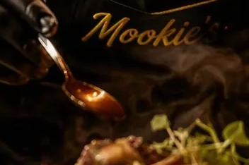 Chef drizzling sauce over food at Mookie's.
