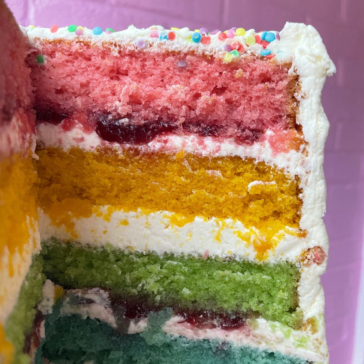 A rainbow vanilla cake layered with jam and buttercream icing. 