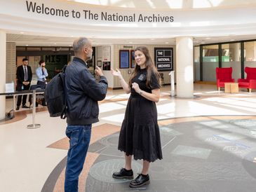 Two people conversing inside The National Archives lobby.