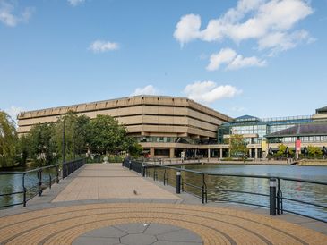 Modern building beside a water body under a partly cloudy sky.