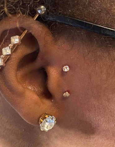 Close-up of an ear with multiple piercings and diamond-like studs.