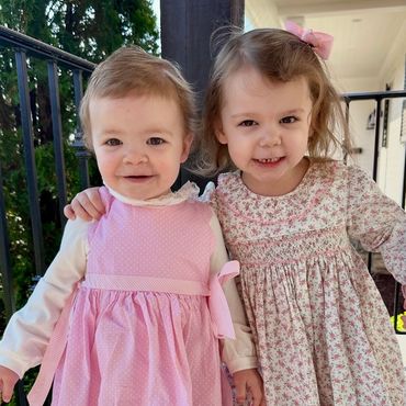 Two toddler girls standing outdoors.