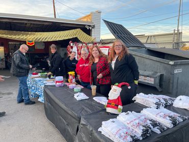 Group of people at an outdoor event selling Santa Toy Run shirts.
