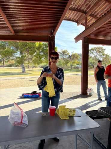 Woman standing under a pavilion holding yellow tickets with a smile.