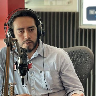 Hombre hablando en micrófono con auriculares.