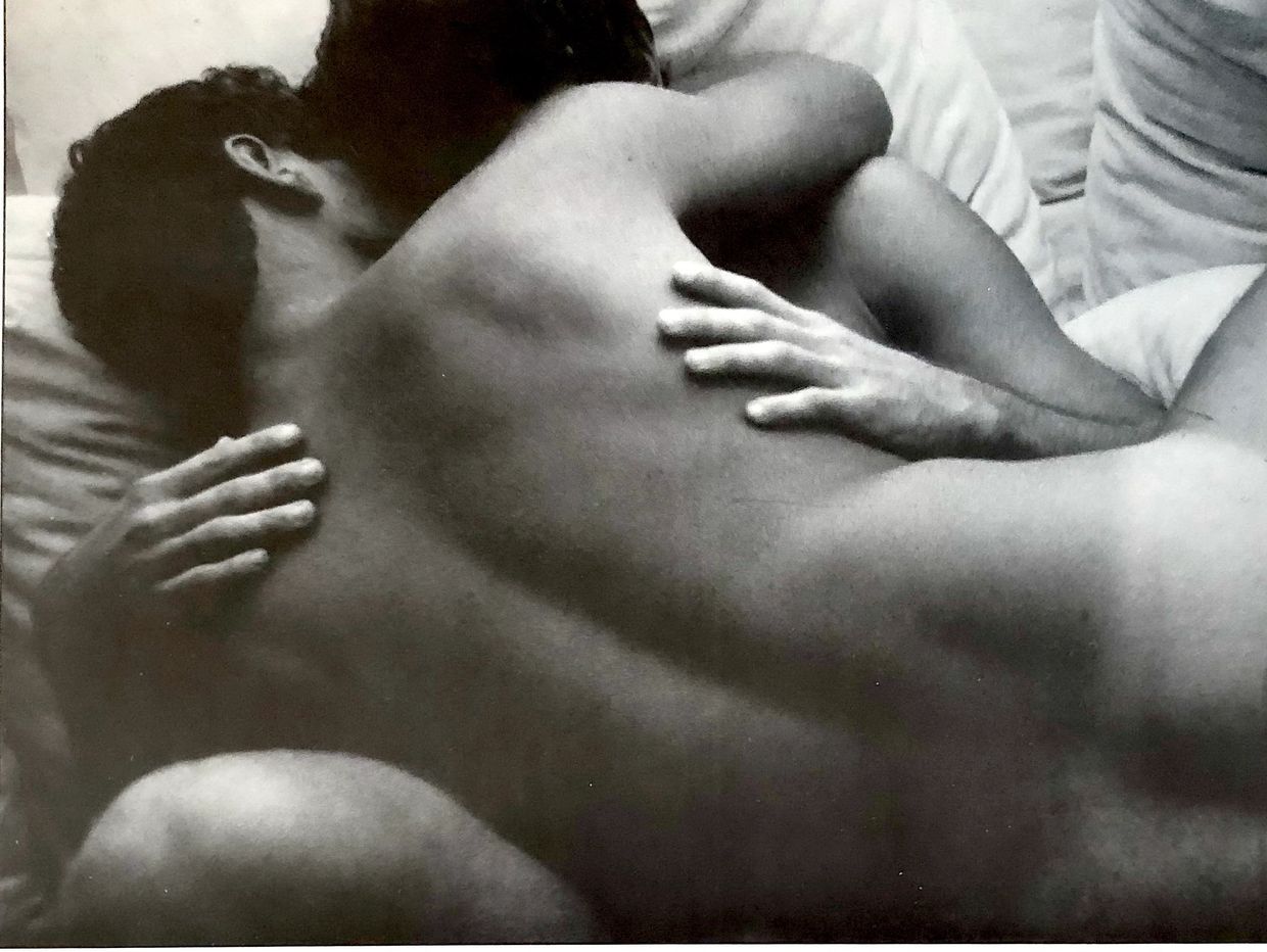 Two men embrace in a photo by Kristen Bjorn taken in the  1980's.