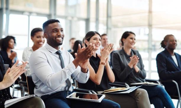 A diverse group of professionals applauding in a modern conference room.