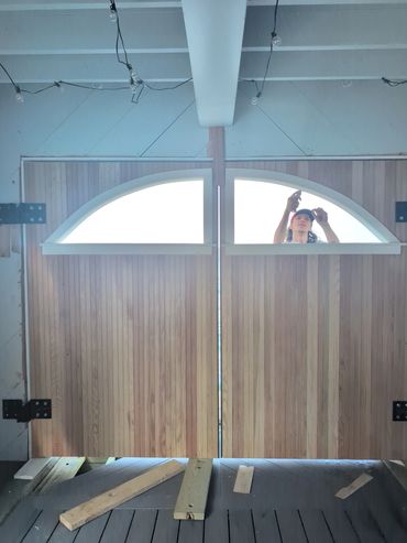 A person working on a large wooden door with arched windows.