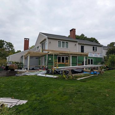 House under construction with wooden framework and building materials on the lawn.