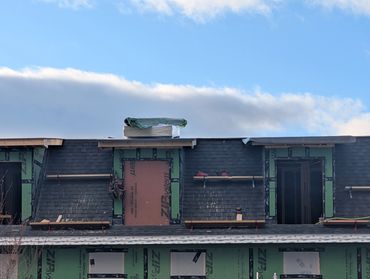 A house under construction with green Zip System sheathing and roofing work.