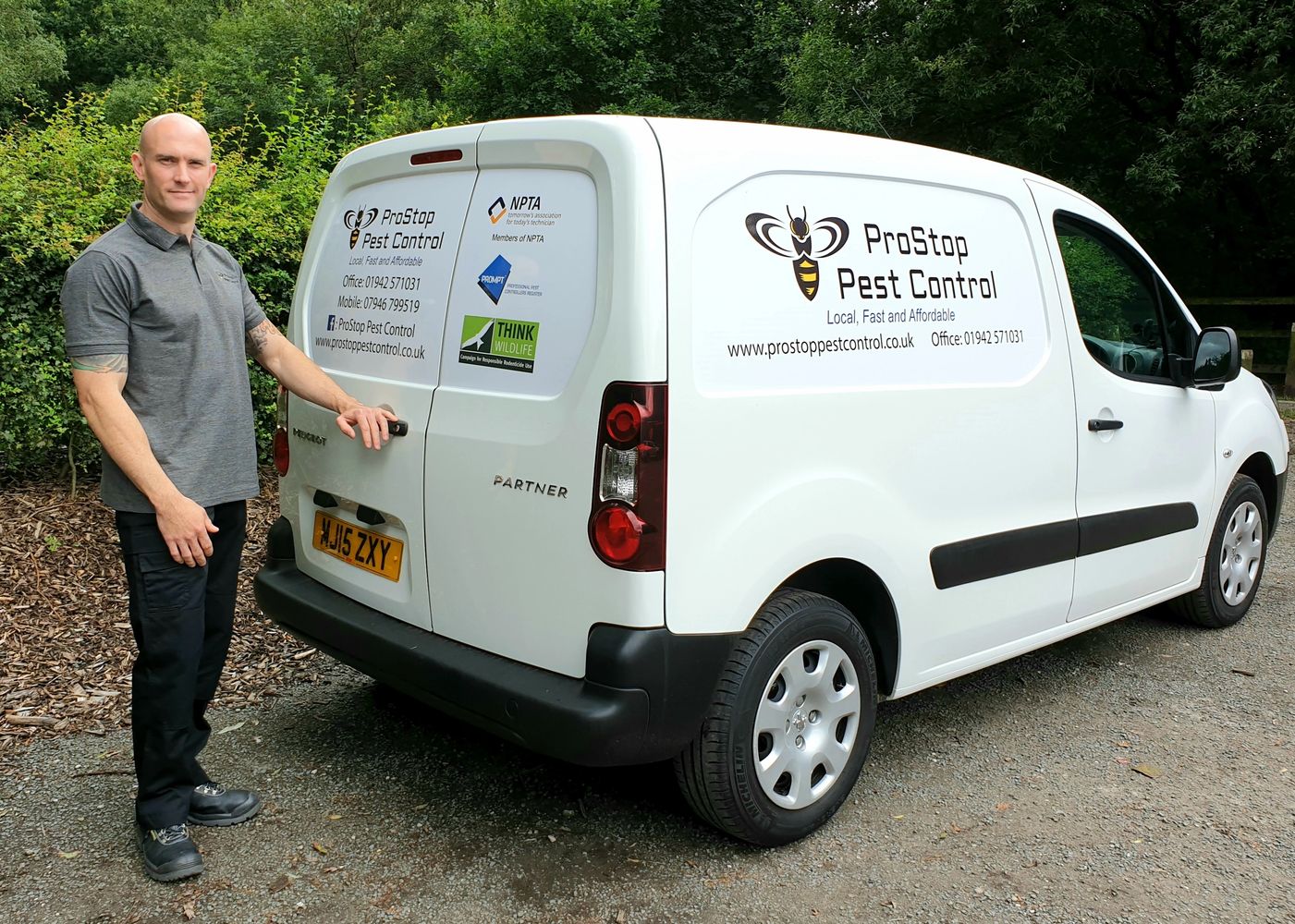 Pest control man stood next to work van.