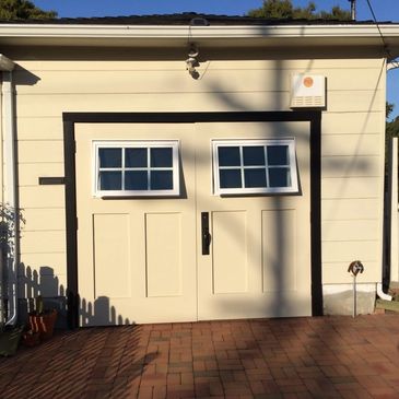 Double garage doors with tilted windows and beige exterior walls.