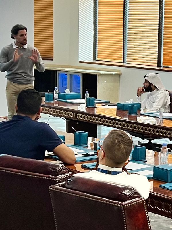 A man presenting to a group seated around a conference table.