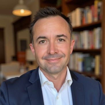 Professional man in a navy suit smiling in a library setting.