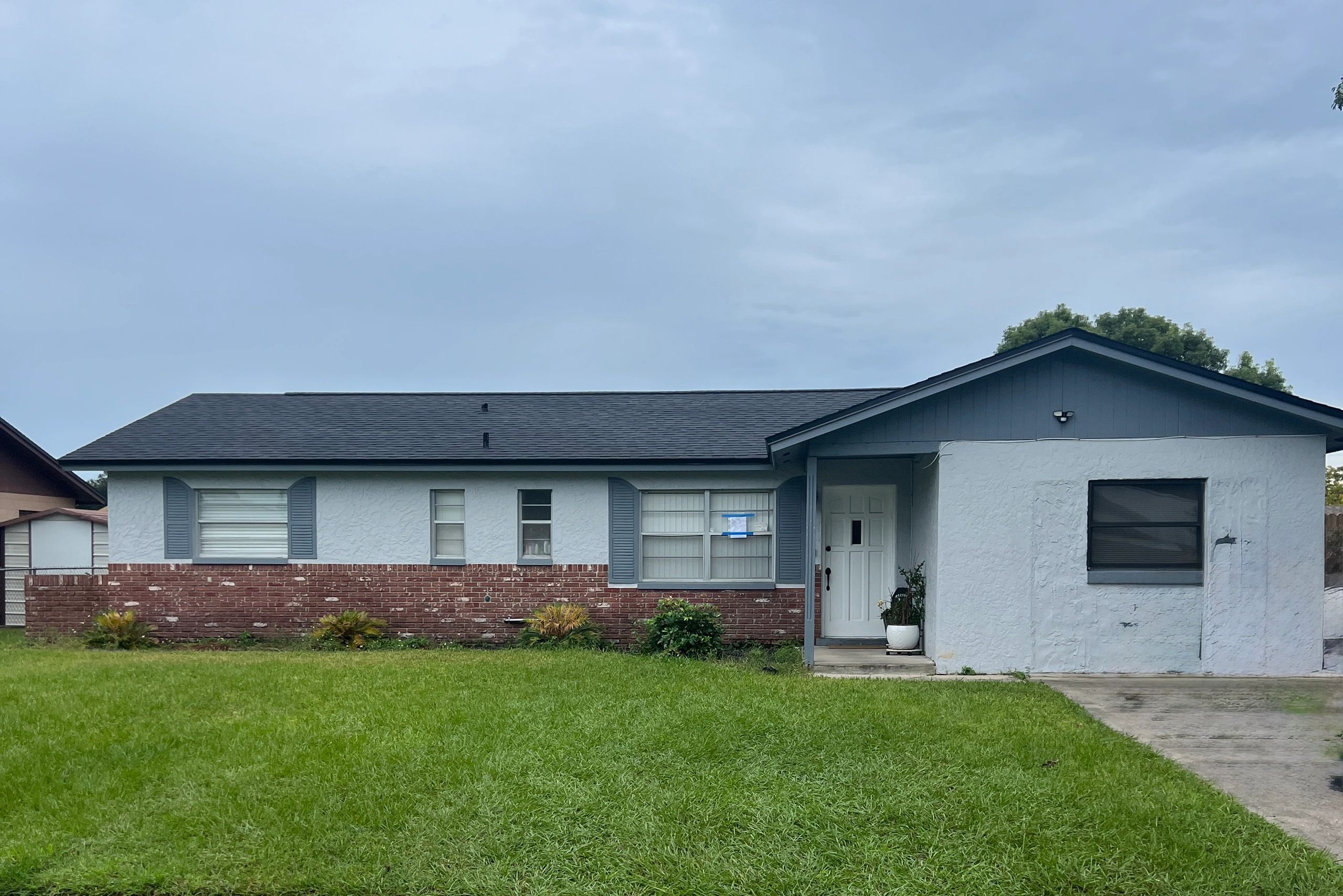 Single-story house with a brick and stucco exterior and a large green lawn.