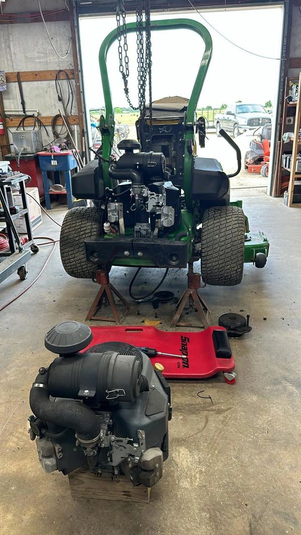 Lawn mower engine removed and placed on a block in a workshop.
