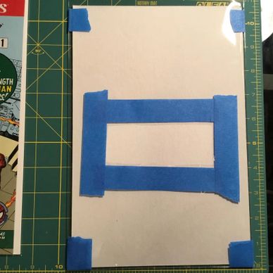 White paper taped on a green cutting mat with blue painter's tape.