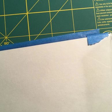 Paper taped on a cutting mat with blue painter's tape.