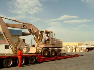 Construction vehicle being loaded onto a flatbed trailer.