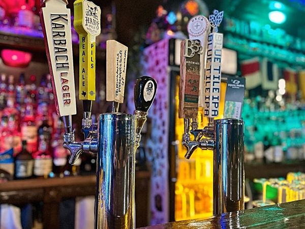 Colorful beer taps lined up in a cozy bar with ambient lighting.