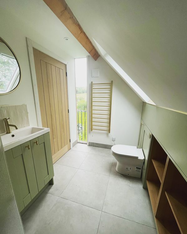 A bright, modern attic bathroom fitted with handcrafted storage, a custom vanity unit, and seamless