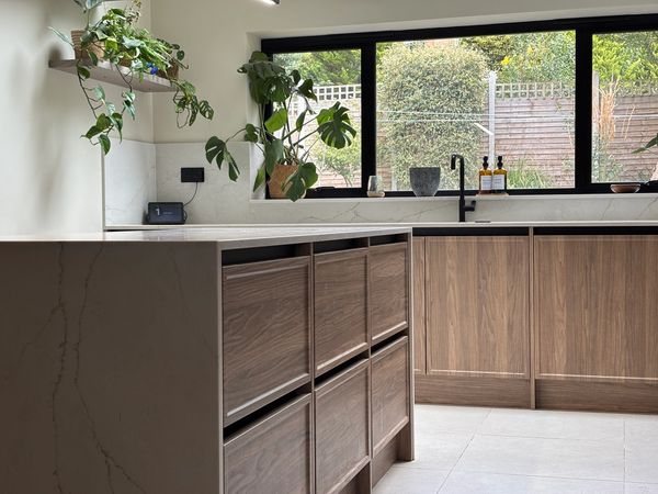 Bespoke modern kitchen in Leamington Spa with walnut cabinets, quartz worktops, and black fixtures.