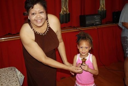 Lady gifting an idol to a small girl, smiling at the camera