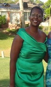 A lady in green dress smiling at the camera